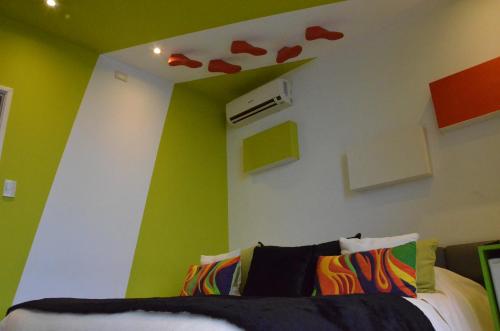a bedroom with green walls and a bed with hearts on the wall at Los Muelles Boutique Hotel in Carmelo
