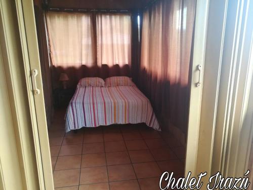 a small bedroom with a bed with a striped blanket at Hotel Chalets Los Volcanes in Alajuela City