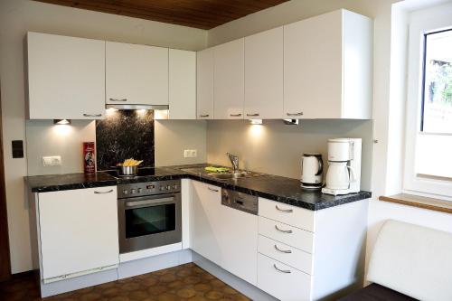 a white kitchen with white cabinets and a sink at Apart Belvita in Sankt Leonhard im Pitztal