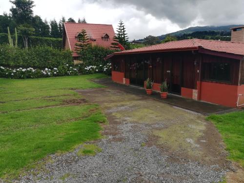 a red building with a yard with a house at Hotel Chalets Los Volcanes in Alajuela City