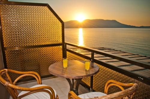 a table and chairs on a balcony with the sunset at Akrogiali in Kissamos