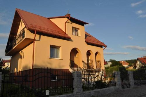 a yellow house with a fence in front of it at Domek Monte Black z jacuzzi i sauną fińską in Stronie Śląskie