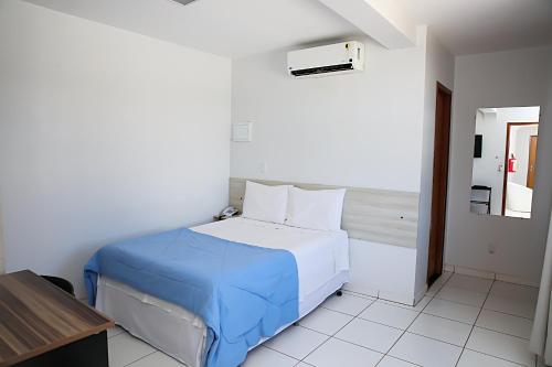 a white bedroom with a bed with a blue blanket at Bellonorte Hotel in Altamira