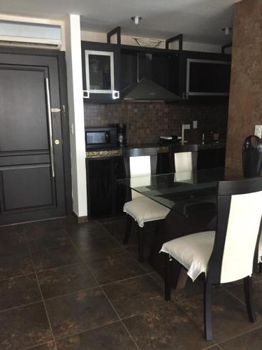 cocina con mesa negra y sillas blancas en Punta Centinela Apartment, en Punta Blanca