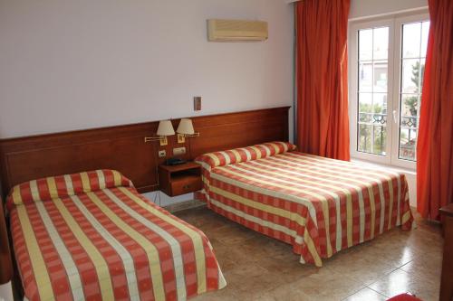 a hotel room with two beds and a window at Gran Hostal El Chiscón in Colmenar Viejo