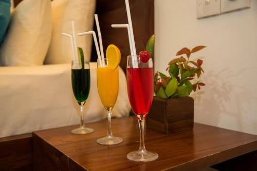 three wine glasses sitting on top of a wooden table at Anantamaa Hotel in Trincomalee