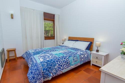 1 dormitorio con 1 cama con edredón azul y ventana en Torralta Apartment, en Alvor
