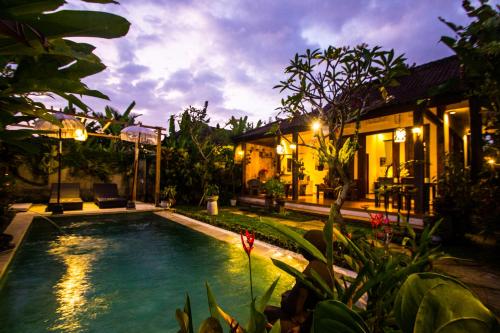 a pool in front of a house at night at Villa Ulun Mertha - 1BR Private Villa in Ubud