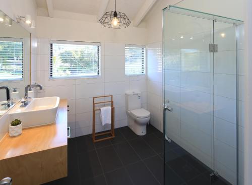 a bathroom with a toilet and a glass shower at Church Bay Views in Oneroa