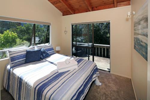 a bedroom with a bed and a large window at Church Bay Views in Oneroa