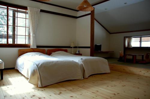 a bedroom with a white bed in a room with windows at Il Bosco in Hakuba
