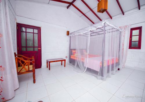 a bedroom with a canopy bed and a red door at Latheena Resort in Weligama