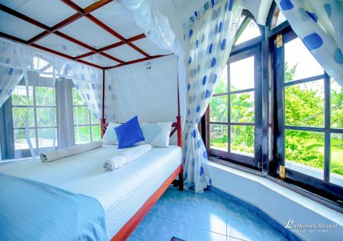 a bedroom with a bed and windows in a room at Latheena Resort in Weligama