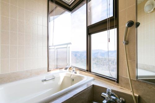 a bathroom with a bath tub and a window at Hotel G-Style in Sayo
