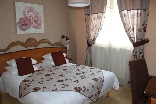 a bedroom with a large bed and a window at Hôtel Restaurant Le Moulin de Saint Verand in Saint-Vérand