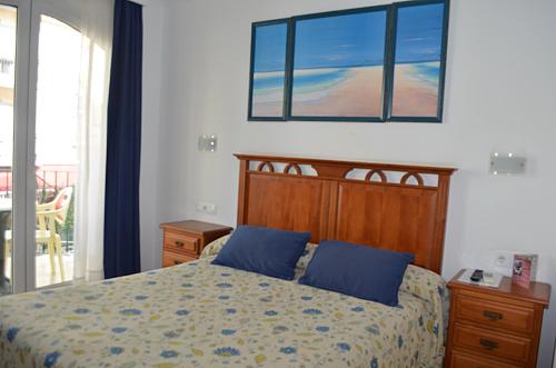 a bedroom with a bed with blue pillows at Plazamar in Torremolinos
