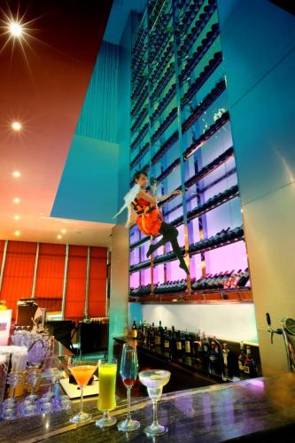 a woman is jumping in the air over a bar with wine glasses at Cambridge Hotel Medan in Medan