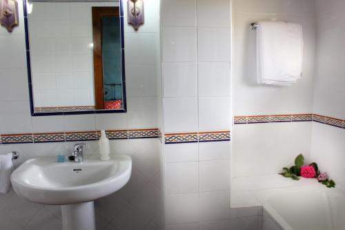 La salle de bains blanche est pourvue d'un lavabo et d'un miroir. dans l'établissement Hotel Doña Sancha, à Covarrubias