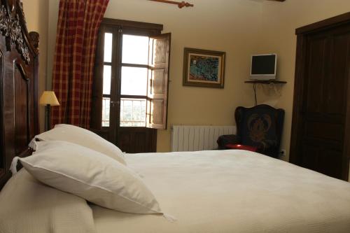 a bedroom with a bed with white sheets and a window at Casa Rural Rincón de la Fuente in Buenaventura