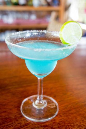 a blue drink with a lime on a wooden table at Visal Sak Guesthouse in Kep