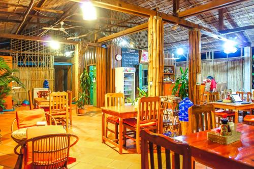 a restaurant with wooden tables and chairs and a room at Visal Sak Guesthouse in Kep