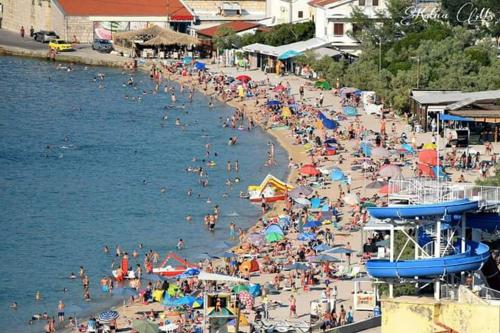 a crowded beach with a lot of people in the water at Apartments Lidija in Pag