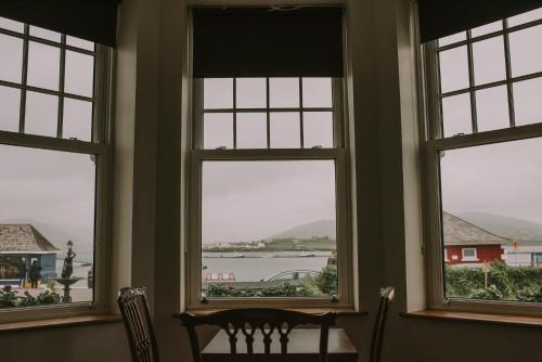a room with three windows with a table and chairs at Royal Valentia Hotel in Valentia Island