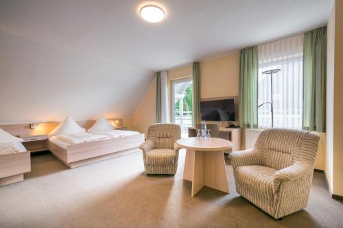 a hotel room with a bed and two chairs and a table at Pension Buchfink in Ueckeritz