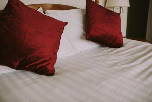 a bed with two red pillows on top of it at Royal Valentia Hotel in Valentia Island