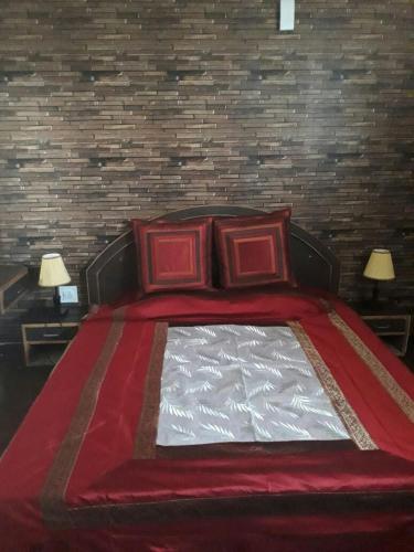 a bed with two red pillows and a brick wall at Trimurti Pine Valley Resort in Shimla