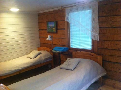 a bedroom with two beds and a window with a table at Ilola Maatilamatkailu in Valkeakoski