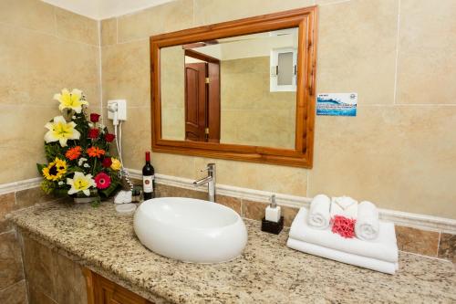 bagno con lavandino, specchio e fiori di Hotel La Joya Isla Mujeres a Isla Mujeres
