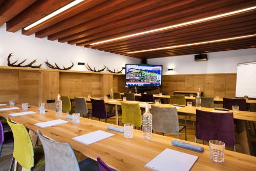 a conference room with tables and chairs and a television at Small Luxury Hotel of the World - DasPosthotel in Zell am Ziller
