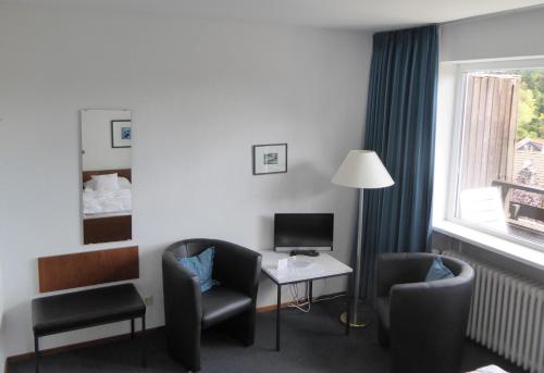a hotel room with a desk and chairs and a television at Bremer Schlüssel in Braunlage