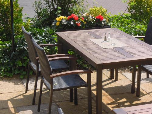 a wooden table and chairs with flowers in the background at Hotel Wiedenhof in Hilden