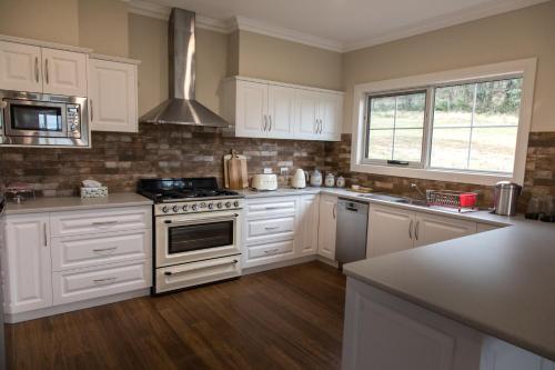 a kitchen with white cabinets and a stove top oven at Mountain Blue Guest House in Deloraine