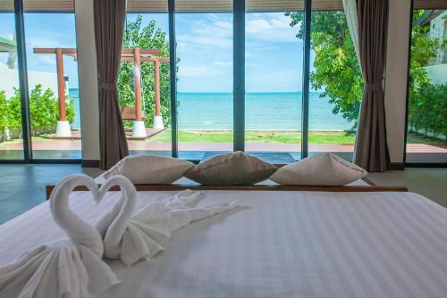 two white swans sitting on a bed with a view of the ocean at Samui Mermaid Beachfront in Bang Rak Beach