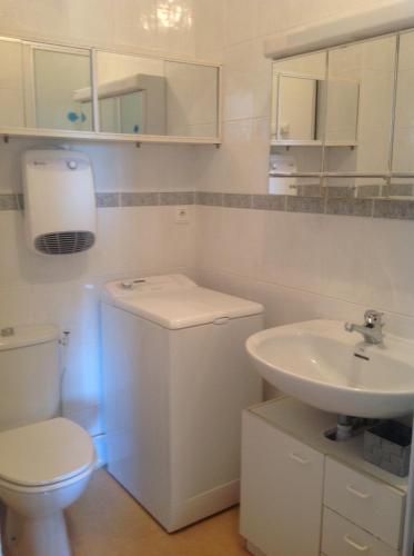 une salle de bain blanche avec des toilettes et un lavabo dans l'établissement Bleu Soleil, à La Grande Motte