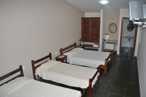 a room with three beds with white sheets at Hotel Termópolis in Termópolis