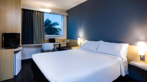 ein Hotelzimmer mit einem großen weißen Bett und einem Fenster in der Unterkunft ibis Vitoria Aeroporto in Vitória