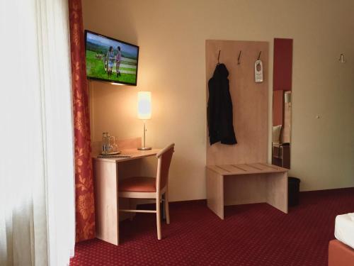 a hotel room with a desk and a television on a wall at Rheinhotel Rüdesheim - Wellness in Rüdesheim am Rhein