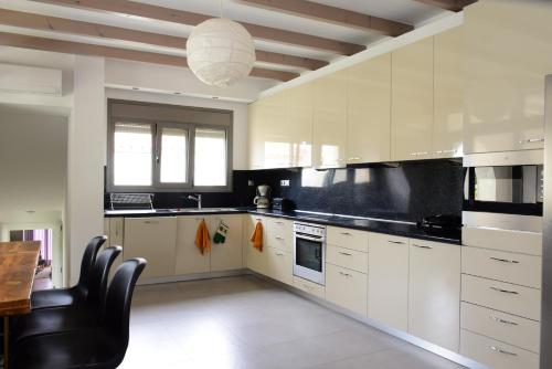 a kitchen with white cabinets and a table and chairs at La Belle Helene in Kymi