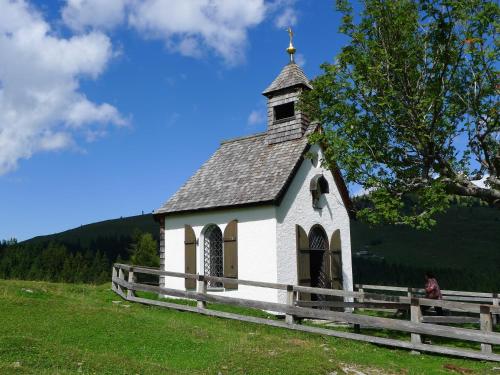 a small white church on a hill with a fence at Alpenhaus Dachstein.Zauber in Abtenau