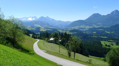 a winding road on a hill with mountains in the background at Alpenhaus Dachstein.Zauber in Abtenau