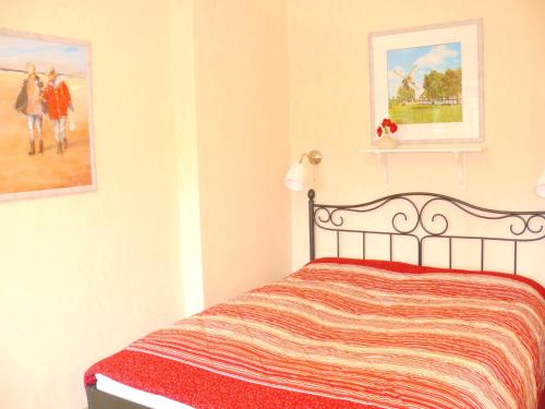 a bedroom with a bed and two pictures on the wall at Apartment Am Mühlendeich in Vollerwiek