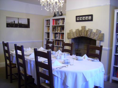a dining room with a table and a fireplace at Megstone House in Seahouses
