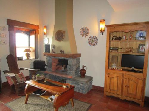 a living room with a fireplace and a tv at Casa Ilhéu - Fajã do Fisher in Feteira