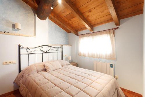 Peñarroya de TastavinsにあるApartamentos La Pastoraの木製の天井のベッドルーム1室(大型ベッド1台付)