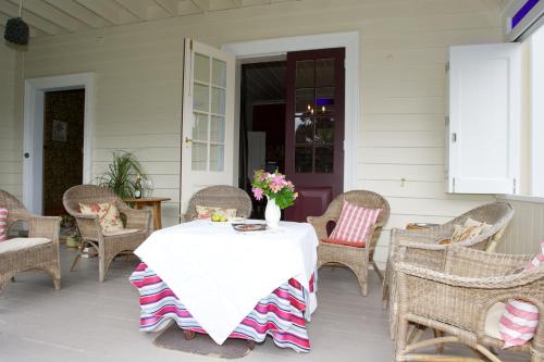 a white table with a vase of flowers on a porch at Cobden Garden in Napier