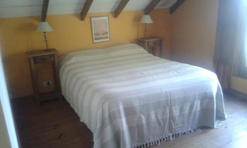 a bedroom with a white bed and two night stands at Cabañas Los Aromos in Tandil